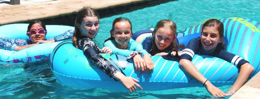 Five girls on floating toys in a swimming pool