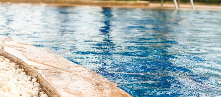 A very full swimming pool, almost overflowing, with rain falling