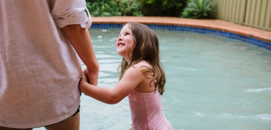 Girl holding hands with a woman beside a pool