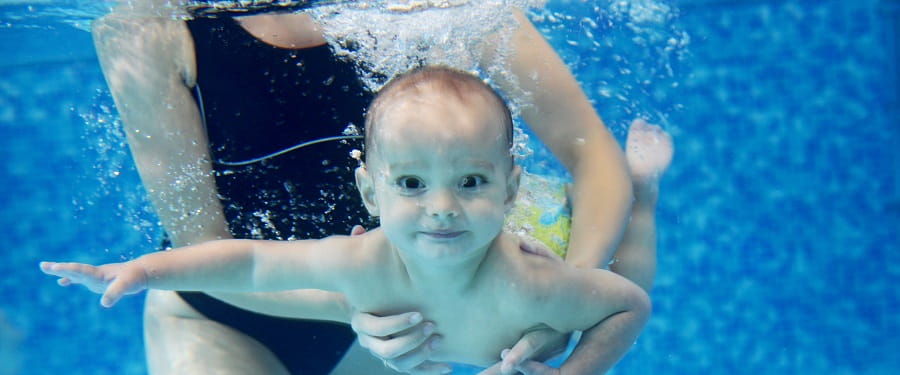baby smiling at camera under water