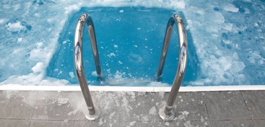 A swimming pool frozen over with a hole made in the ice below the steps