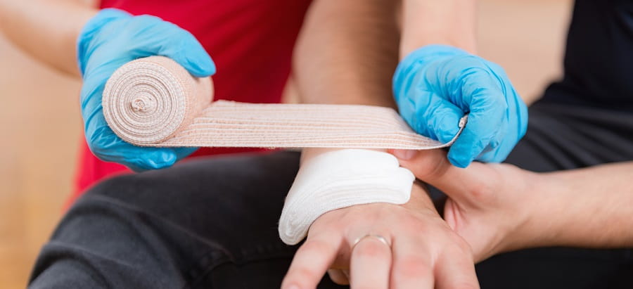 close up of person applying a bandage to another person's wounded arm