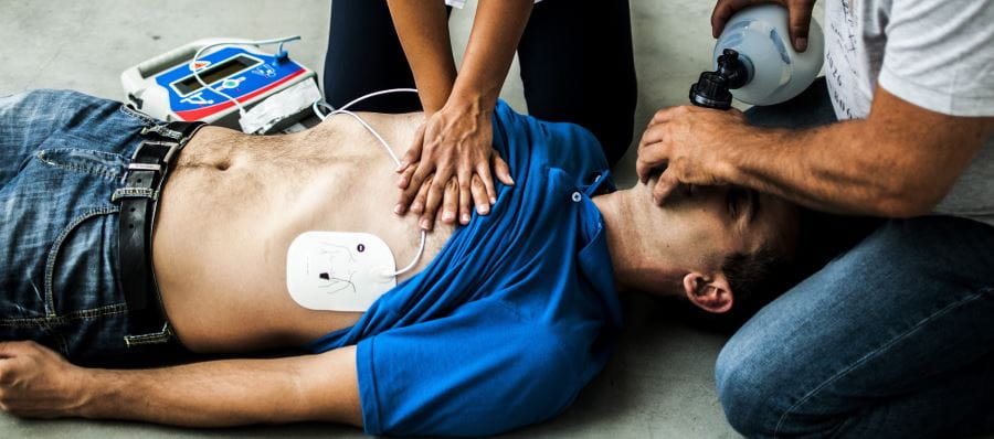 Two people using a defibrillator and performing CPR