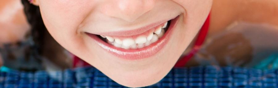 a close up image of a girls mouth as she smiles with teeth showing