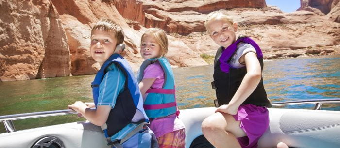 3 children on a boat wearing lifejackets