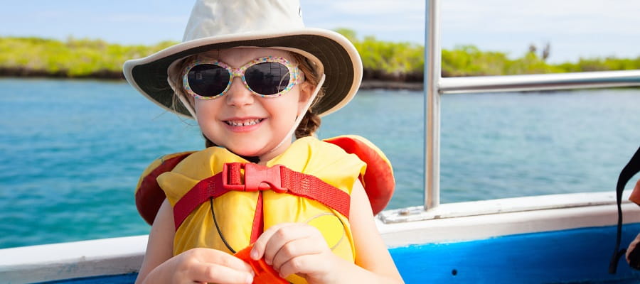 young girl on boat wearing hat, sunglasses and lifejacket