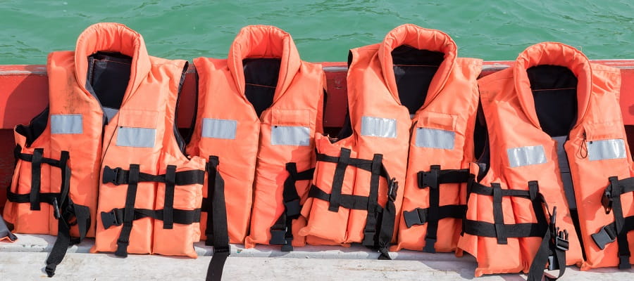 four lifejackets lined up on the edge of a boat